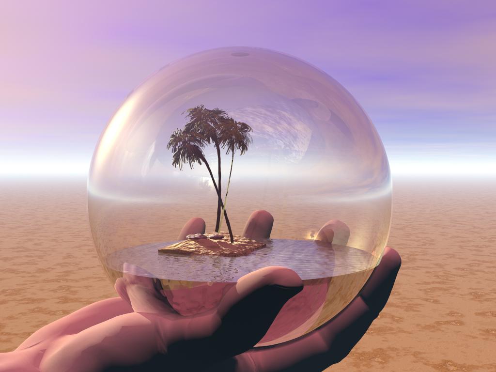  Hand holding glass globe containing an oasis with palm trees.